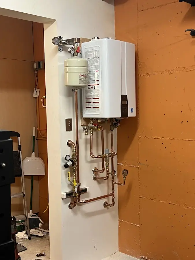 Plumbing technician inspecting water heater connections in Andrews AFB
